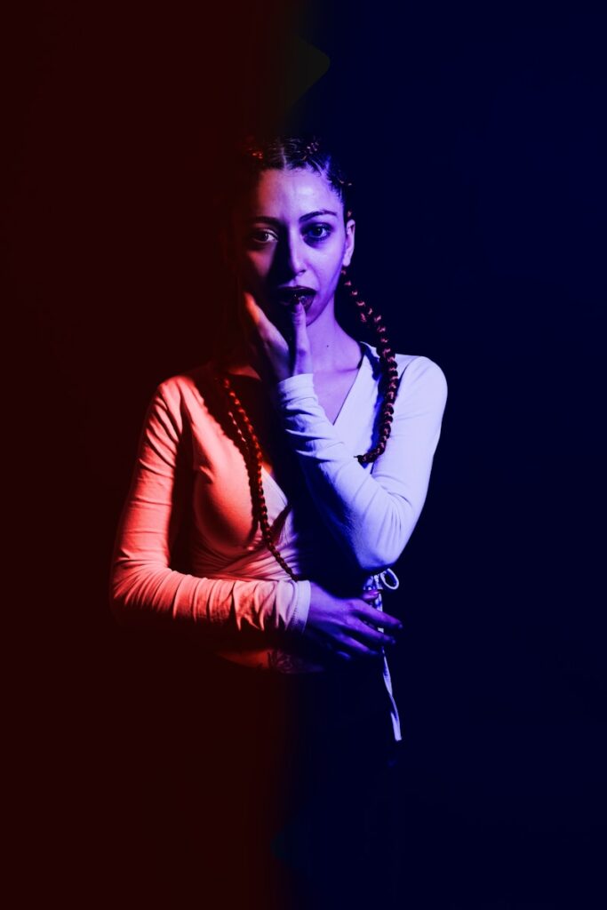 a woman in a white shirt is holding her hand to her mouth